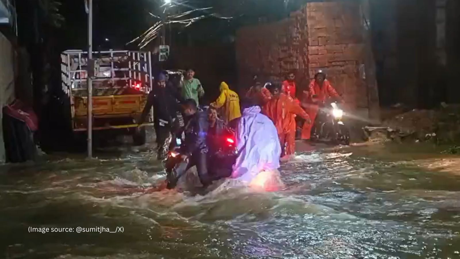 The footage shows men in Swiggy and Zomato jackets wading through waist-deep water, pulling a motorbike to safety.