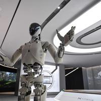 A pair of swivelling, human-like robotic arms, built for physical artificial intelligence research, mirror the motions of an operator in a VR headset twirling his hands like a magician.